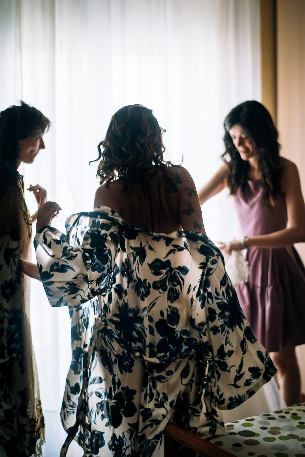 le amiche aiutano la sposa a mettersi l'abito per la cerimonia