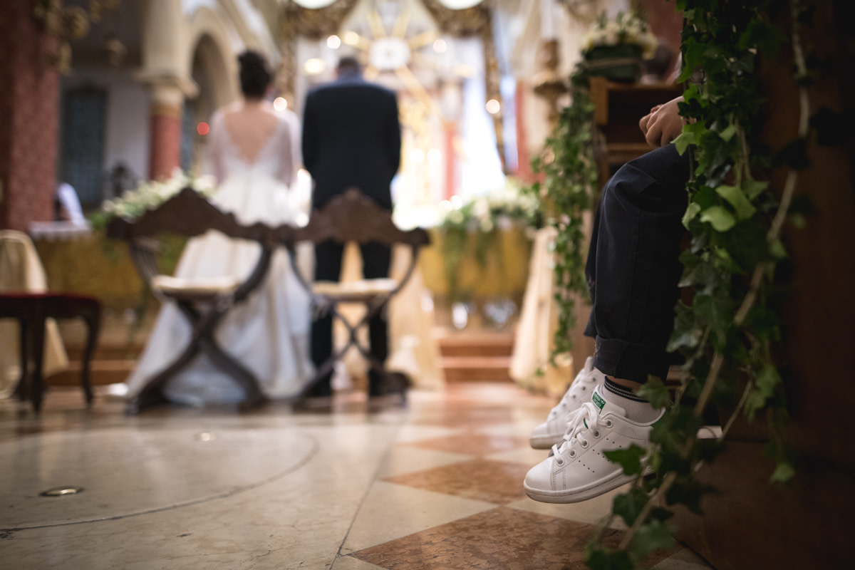 bambino seduto in chiesa al matrimonio con dettaglio sulle scarpe