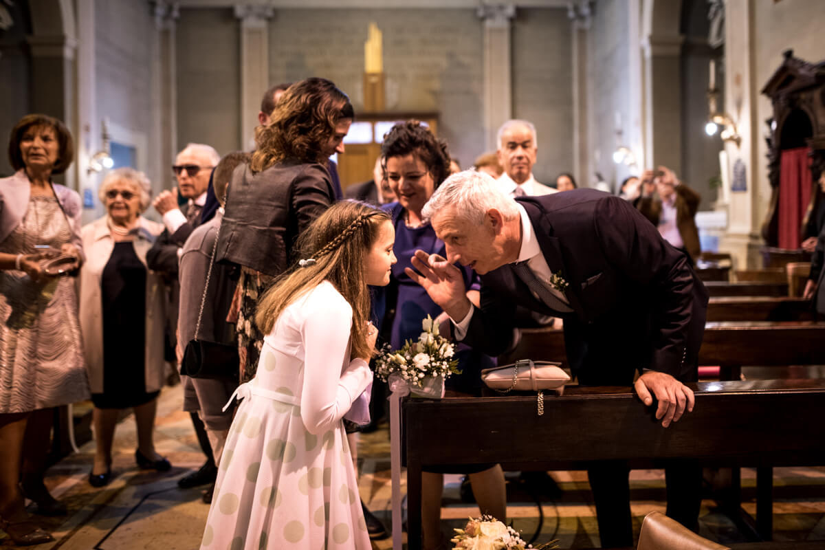 il nonno parla nell'orecchio ala bambina in chiesa
