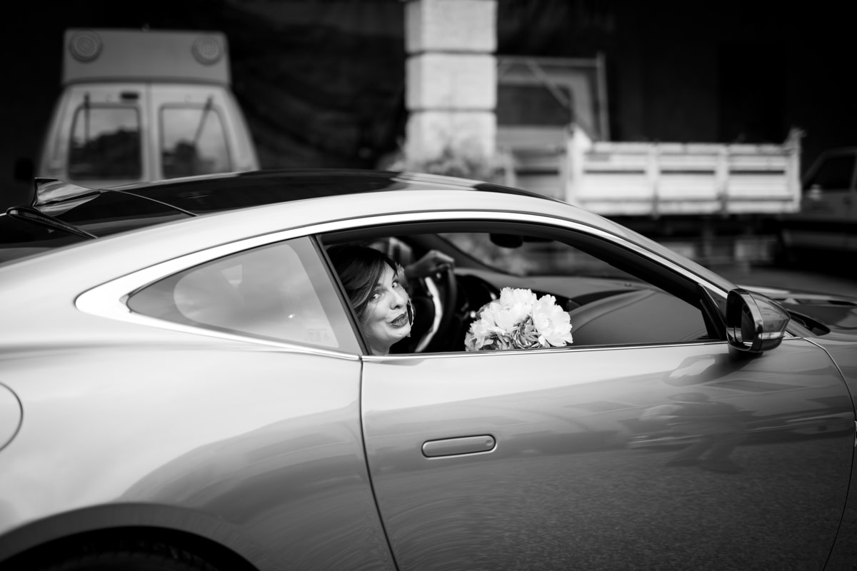 la sposa in macchina con in mano il bouquet all'arrivo al matrimonio