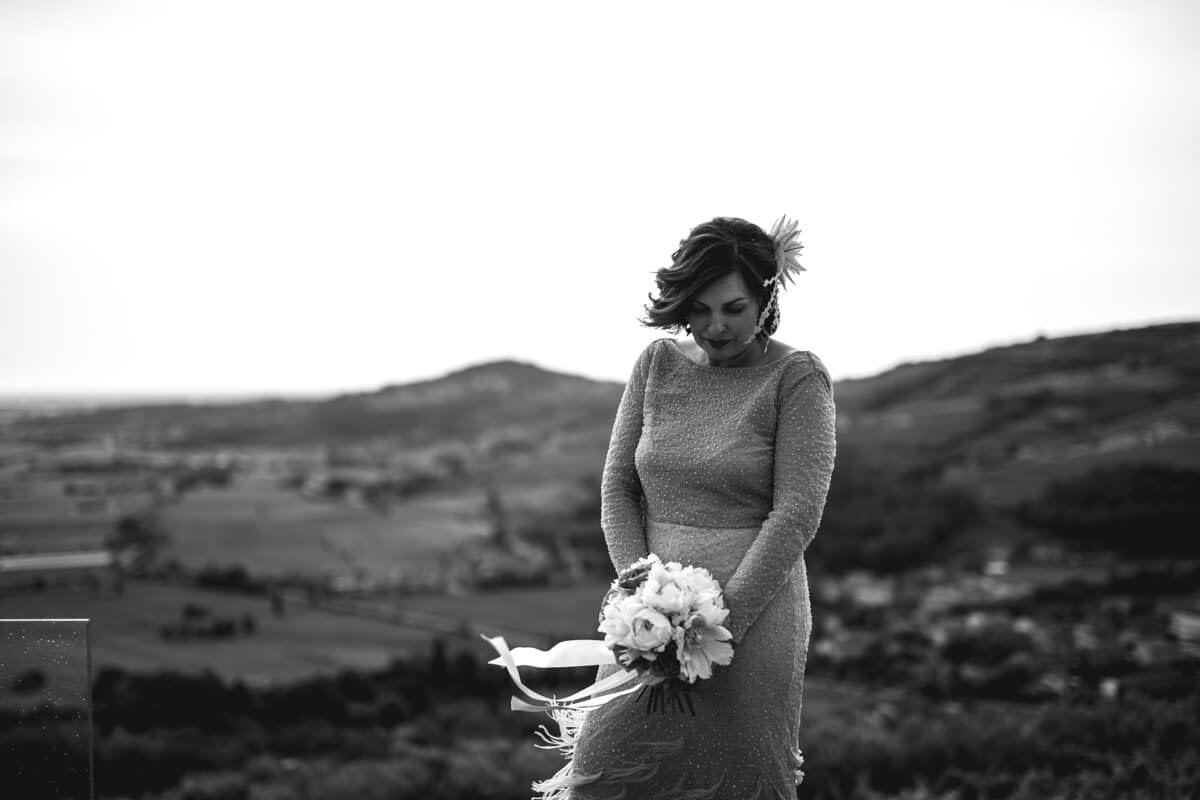 la sposa in abito vintage con in mano il bouquet e come sfondo un bellissimo panorama