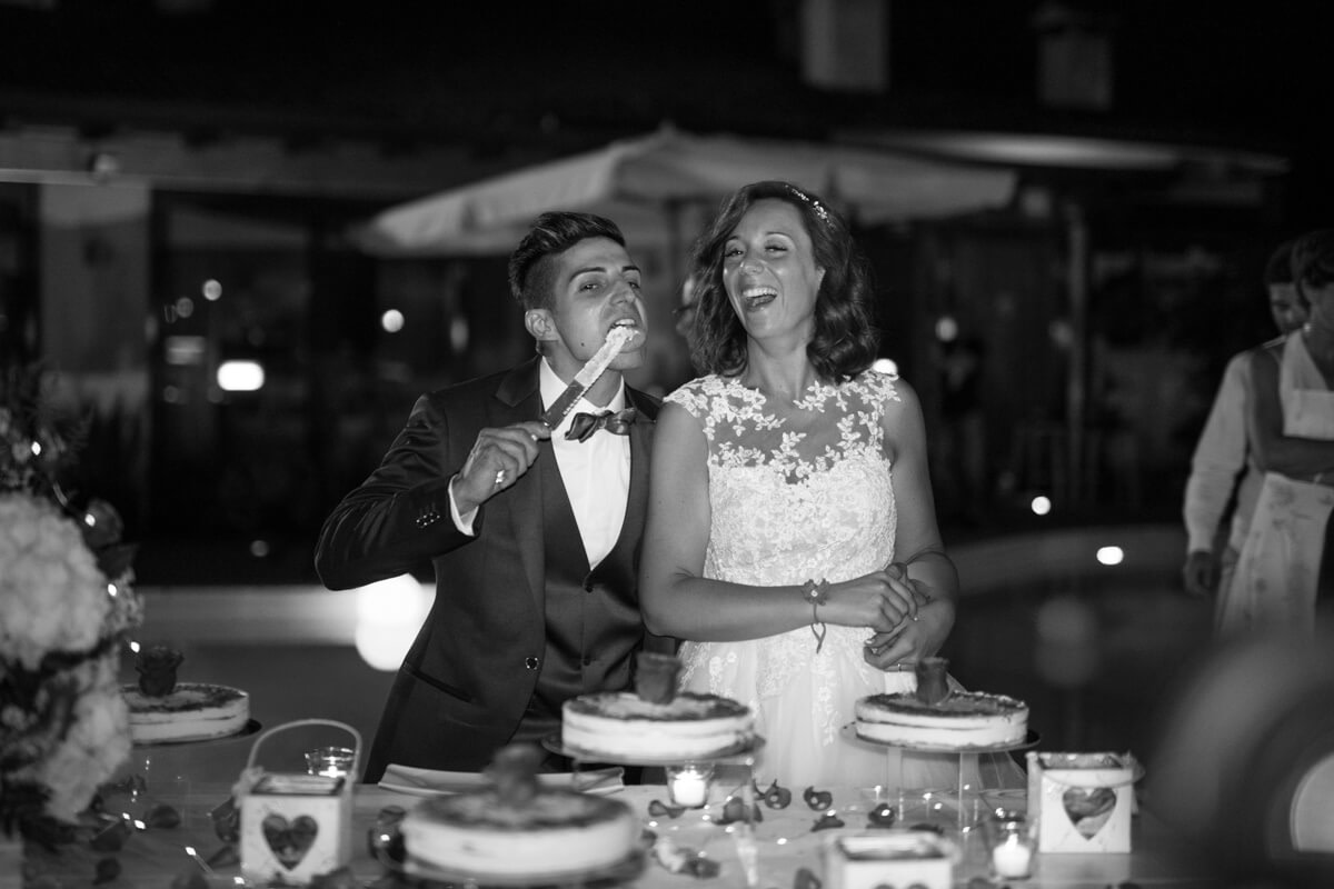 la sposa ride al momento del taglio della torta mentre lo sposo lecca il cartello sporco di panna