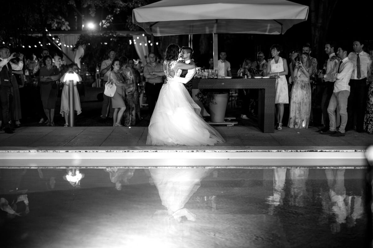 gli sposi in mezzo agli invitati ballano di fronte alla piscina
