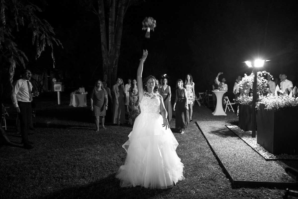 in uno scenario notturno la sposa lancia il bouquet con di dietro le invitate