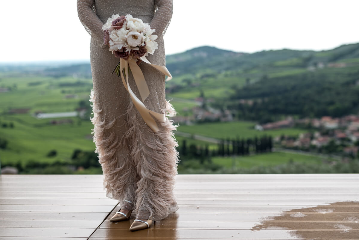 abito da sposa vintage con il bouquet e un bellissimo panorama di colline come sfondo