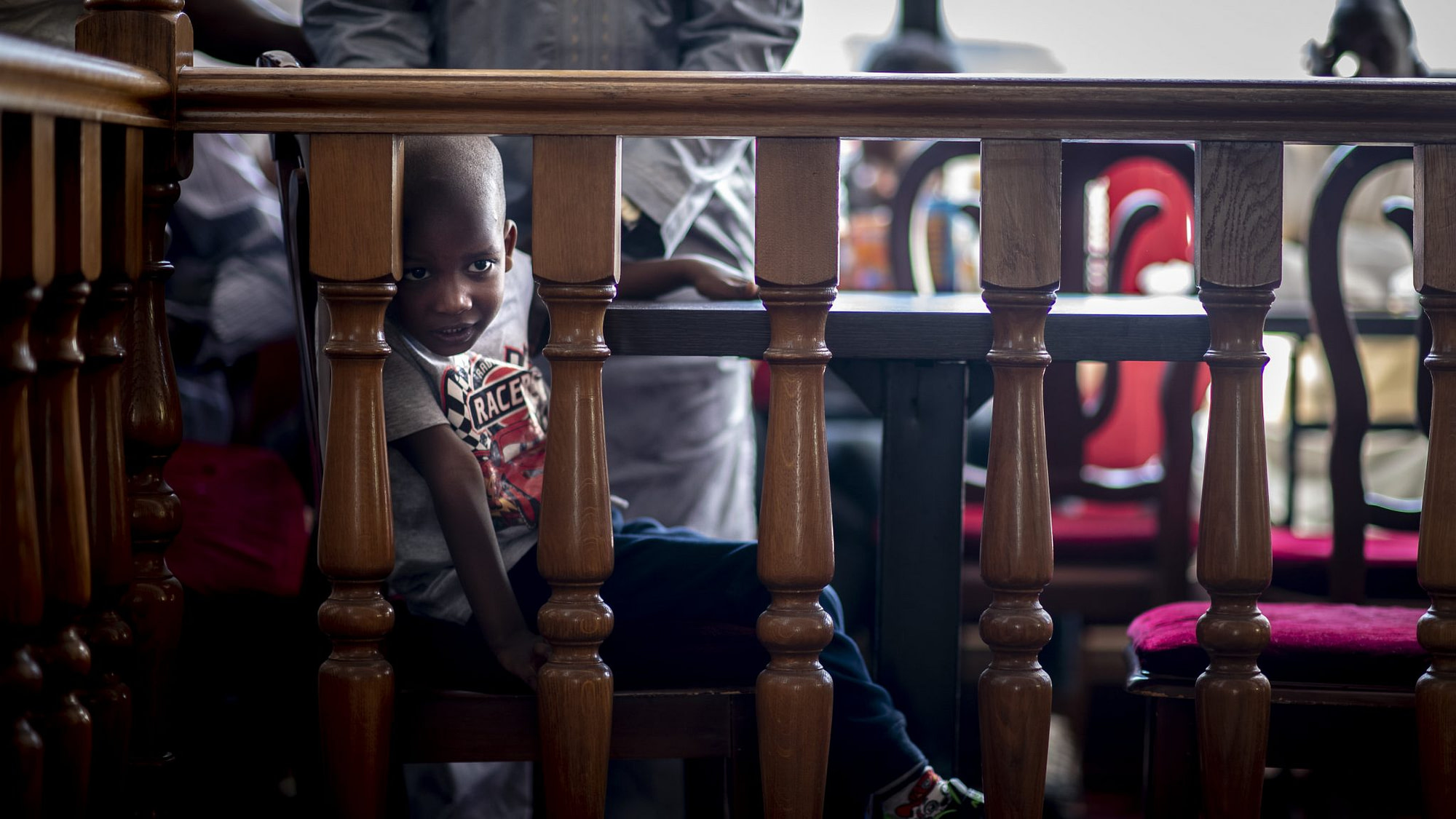 un bambino guarda tra la staccionata del ristorante mentre è seduto al tavolo