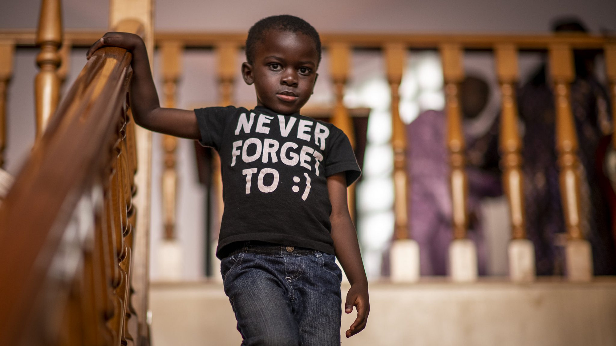 un bambino africano guarda serio il fotografo mentre scende dalle scale