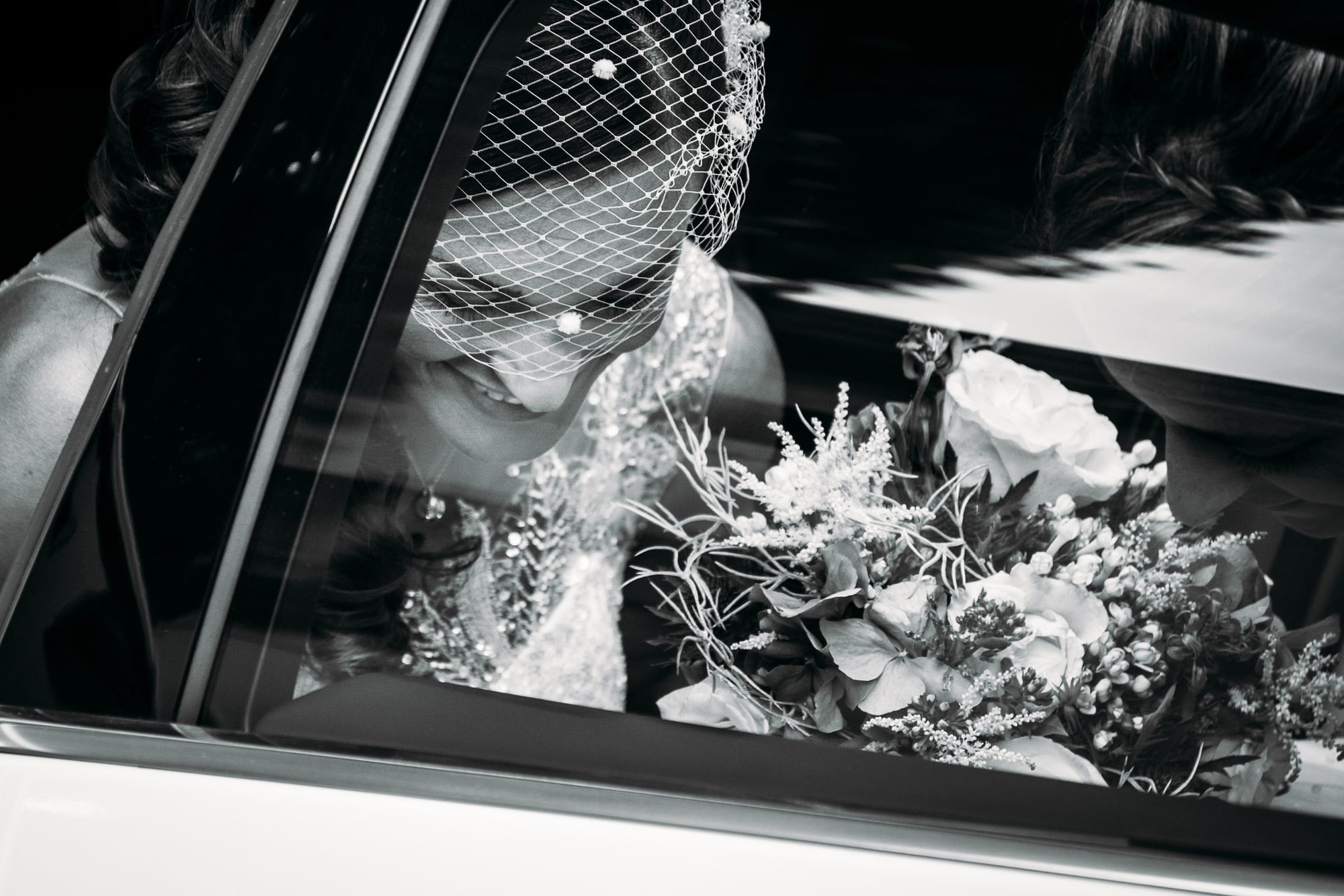 la sposa in macchina con il bouquet in mano