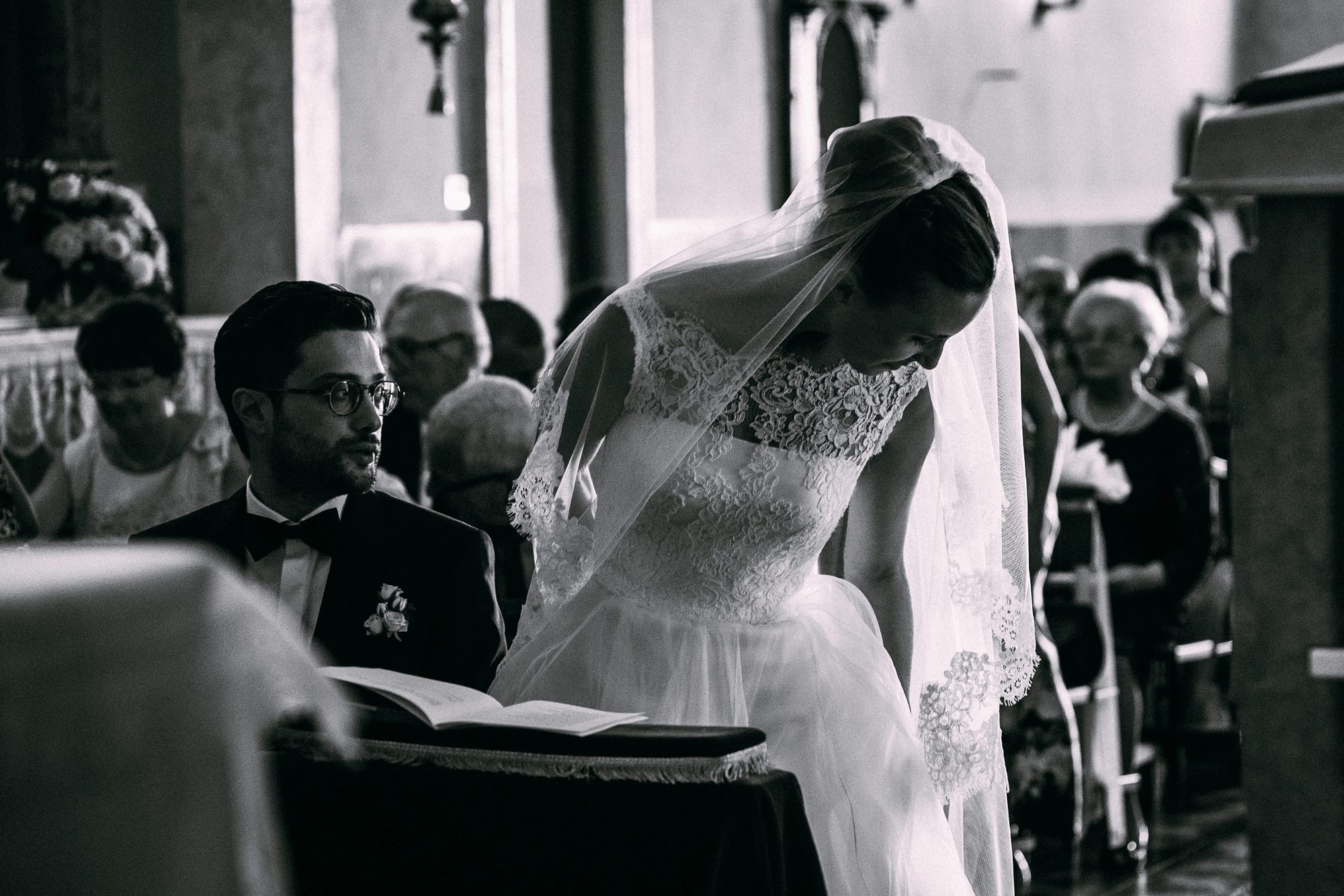 lo sposo guarda la sposa mentre si siede all'altare per l'inizio della cerimonia
