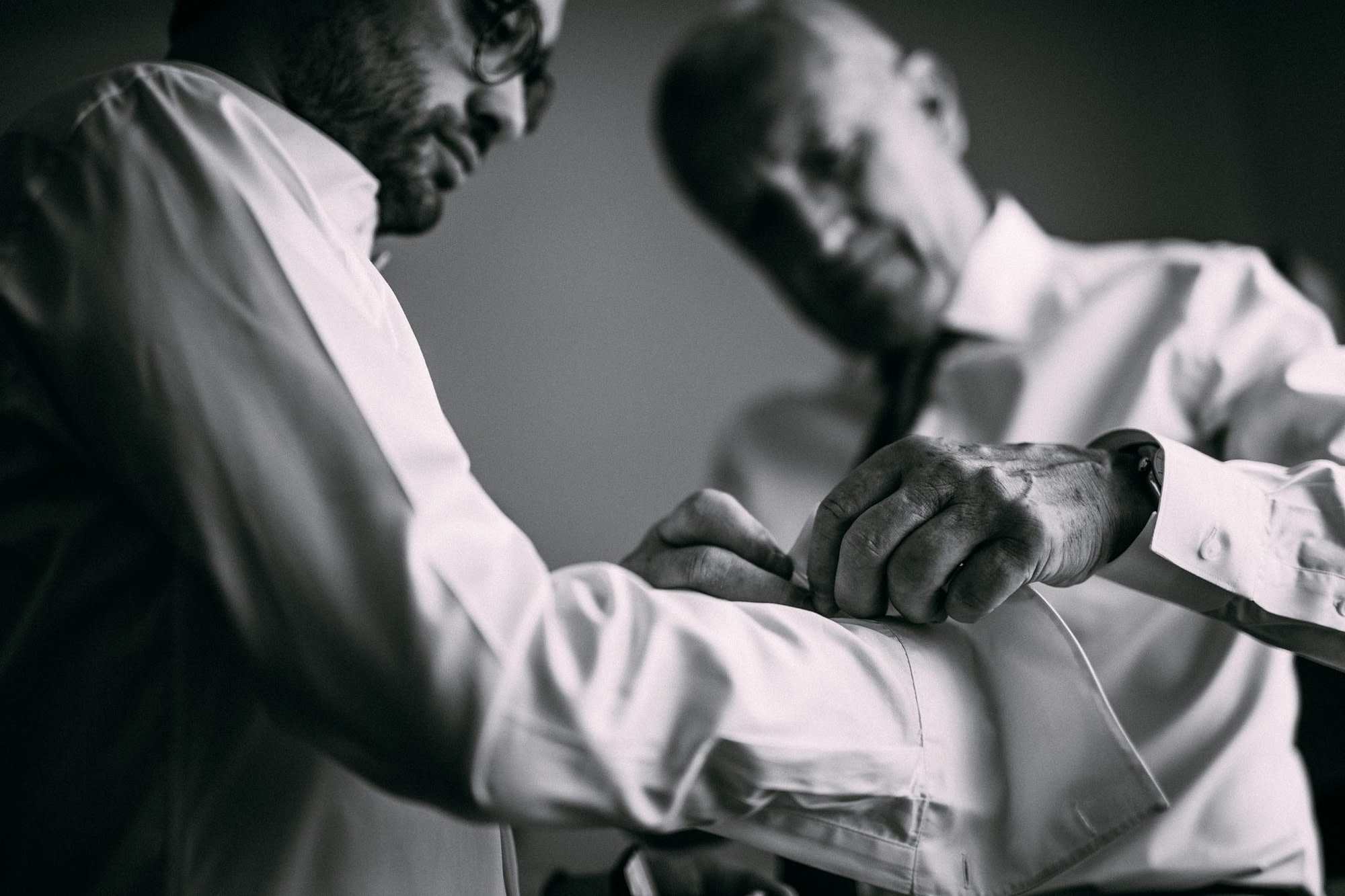il padre aiuta lo sposo ad allacciare i polsini della camicia in preparazione al matrimonio