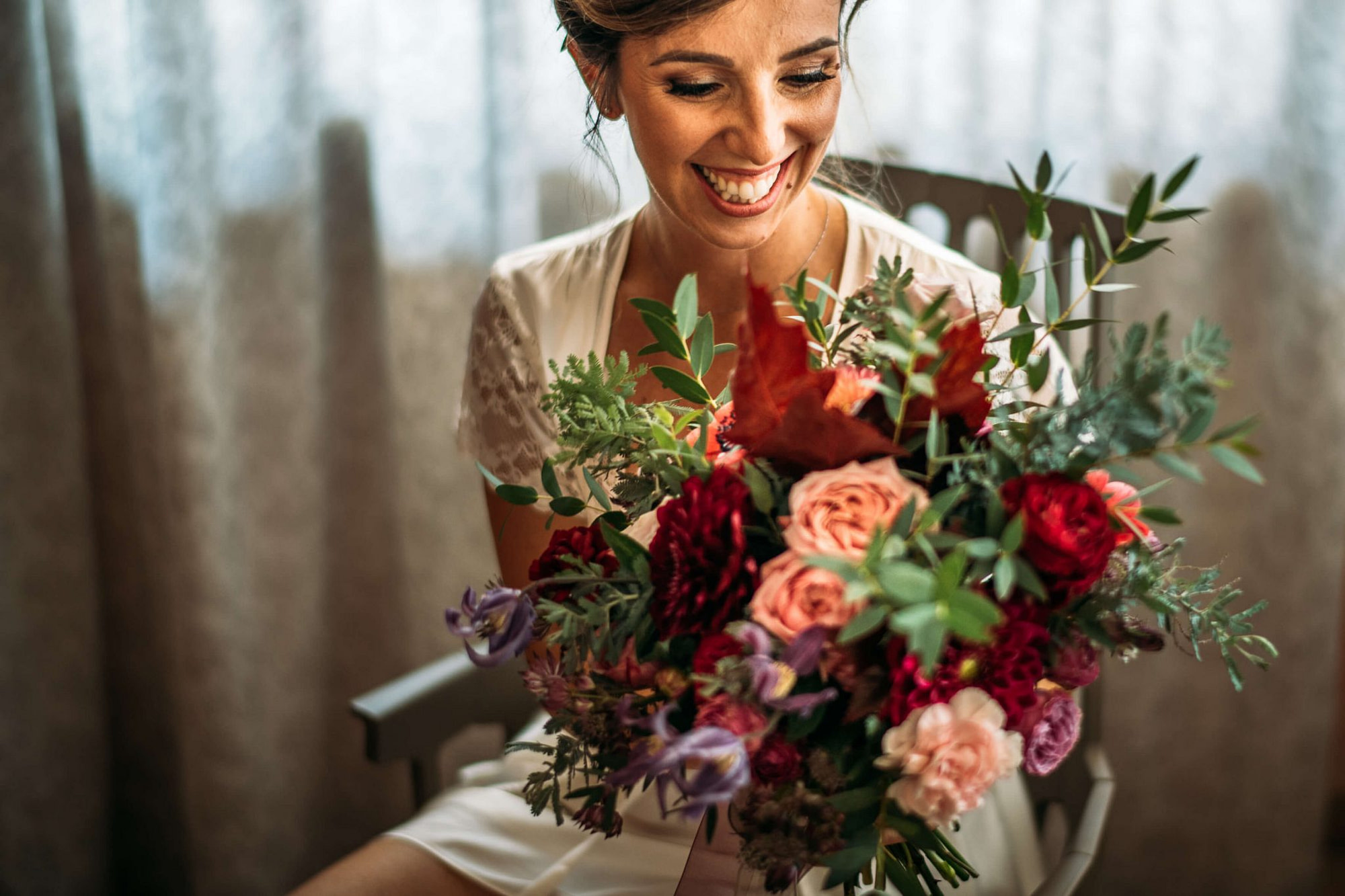 la sposa sorride felice tenendo in mano il bouquet