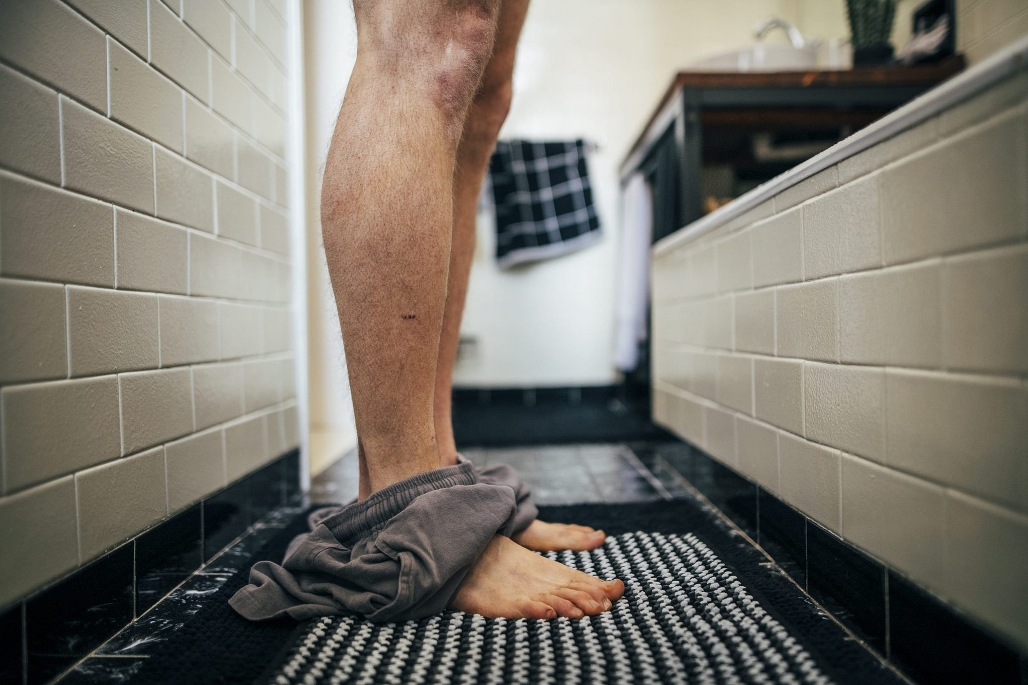 il dettaglio delle gambe con i pantaloncini per terra prima di entrare nella doccia
