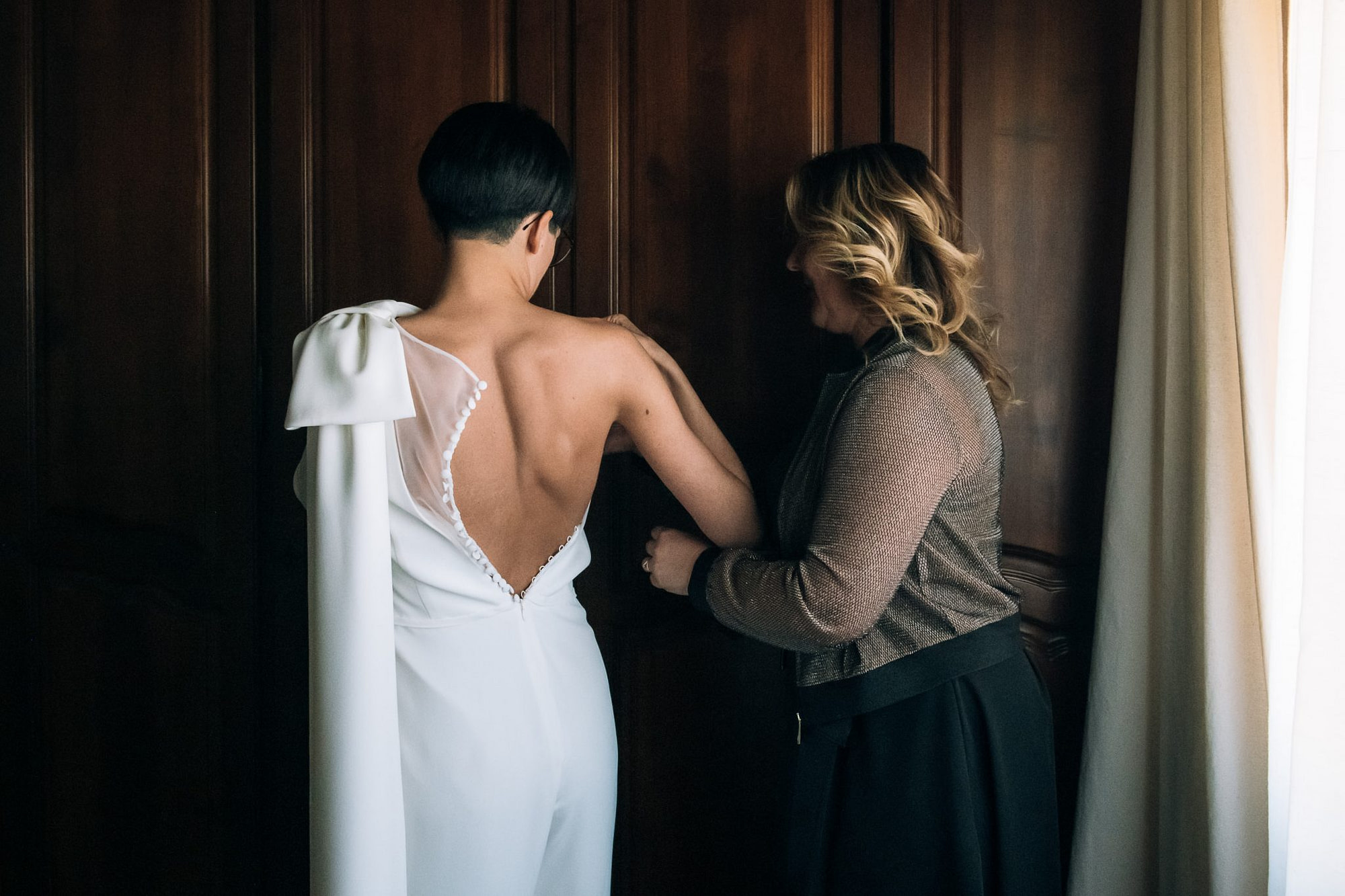 la sposa aiutata dall'amica si infila l'abito per la cerimonia